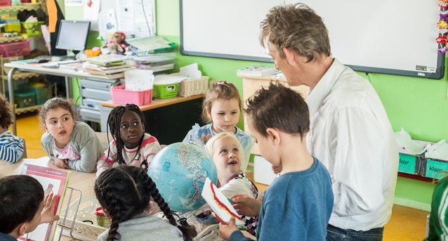 Een leraar geeft les aan een groepje kinderen.